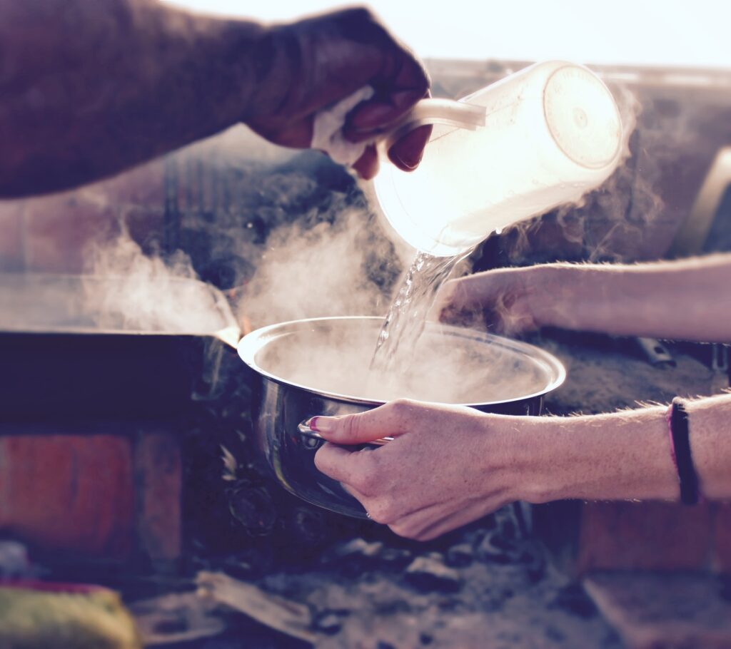A man pouring hot water into a pot, with steam rising.